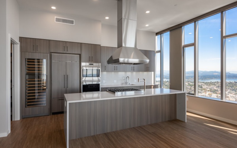 Penthouse kitchen with walk-in pantry, full size wine cooler, paneled refrigerator, double wall ovens, island with waterfall edge and gas cooktop.