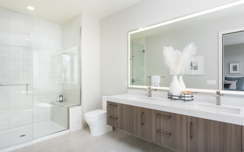Bath features tiled walk-in shower, floating vanity with backlit mirror, tiled flooring and linen closet.