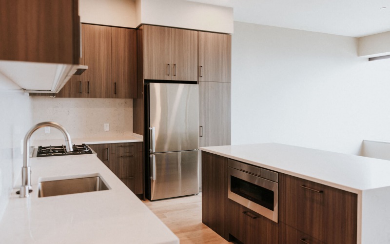 Kitchen in dark color scheme showing quartz countertops and microwave drawer.