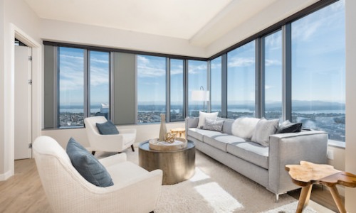 Living room with plank-style flooring and panoramic city, mountain and water views.