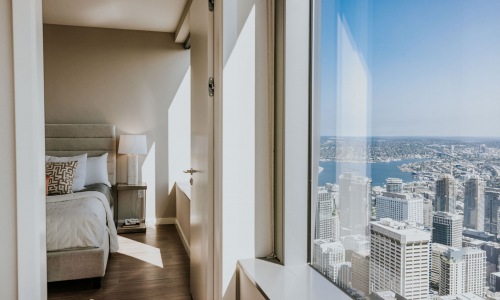 Bedroom with plank-style flooring and sweeping views of the skyline.